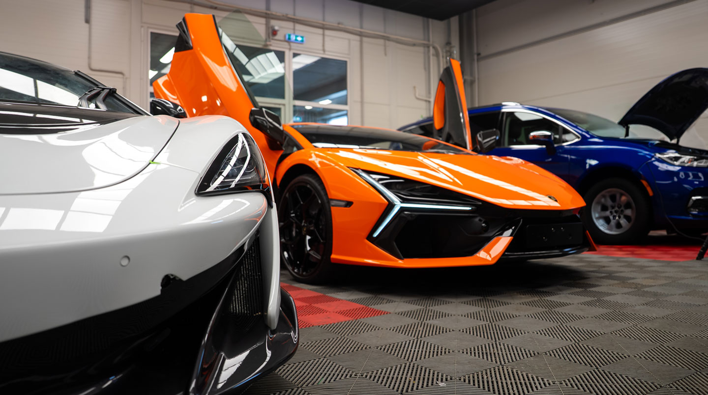 Vue intérieure atelier automobile spécialisé McLaren montrant véhicules en maintenance sur ponts professionnels dans environnement technique organisé avec équipements diagnostic